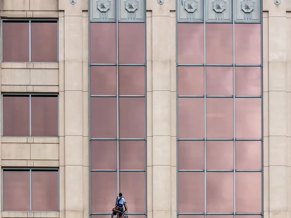 Técnico de trabajos verticales realizando una instalación en la fachada de un edificio alto