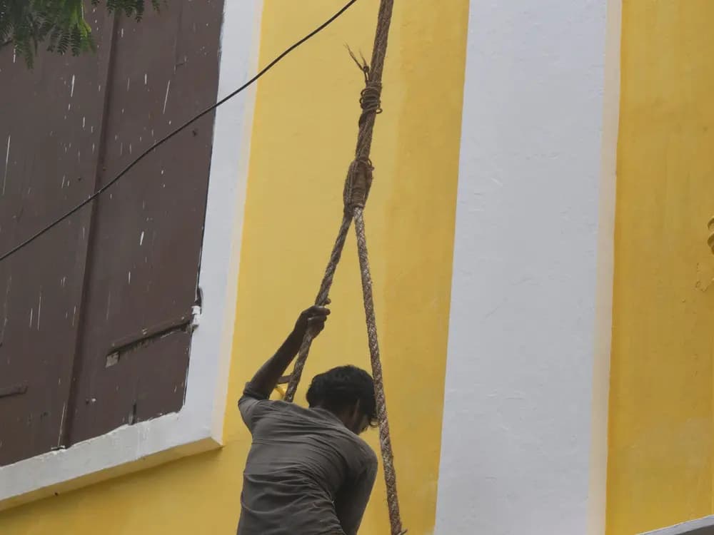 Técnico pintando la fachada de un edificio suspendido con cuerdas